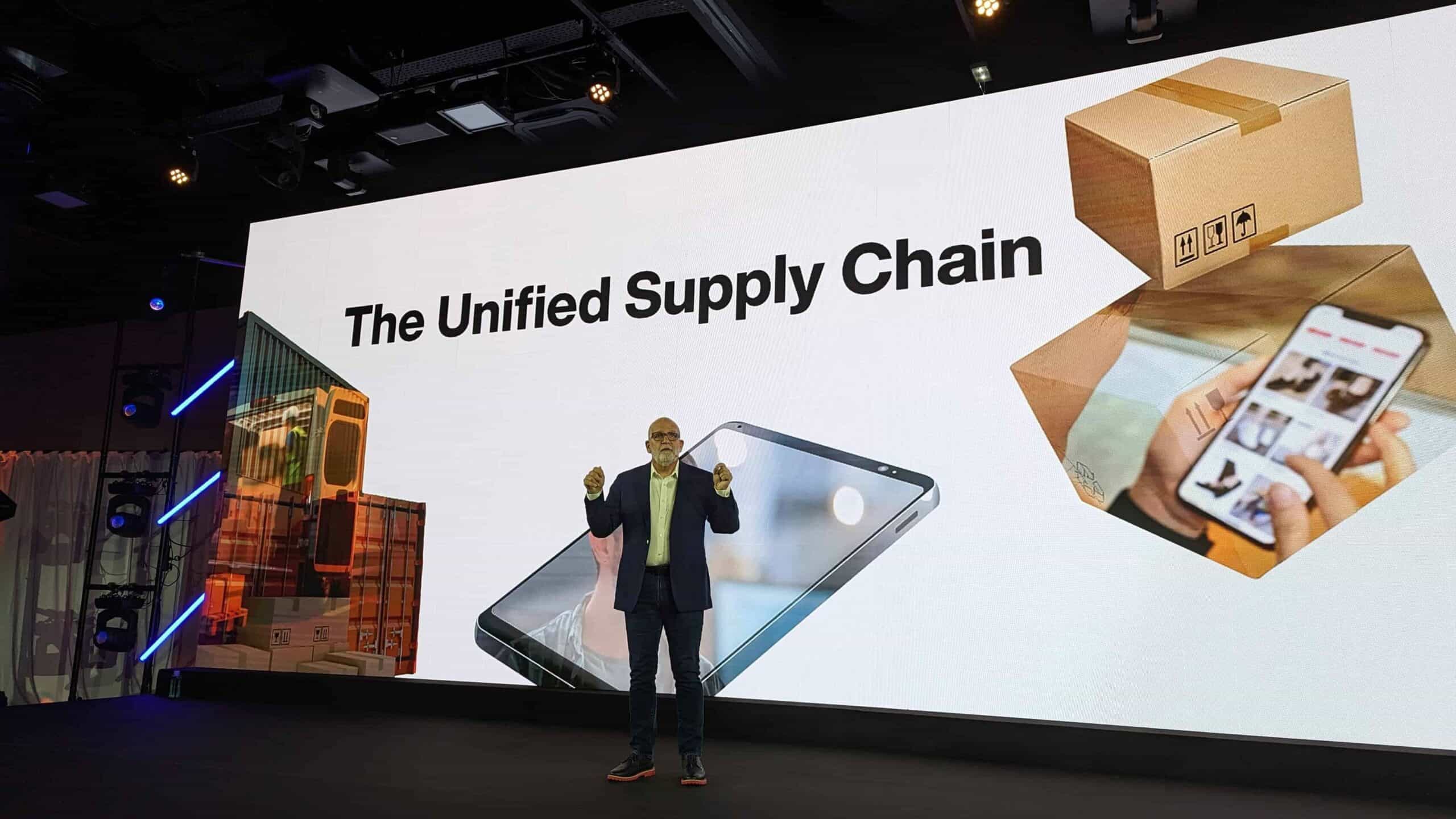 PXL_20231010_082501471 Een man staat voor een groot scherm met de woorden unified supply chain powered by Manhattan Associates.