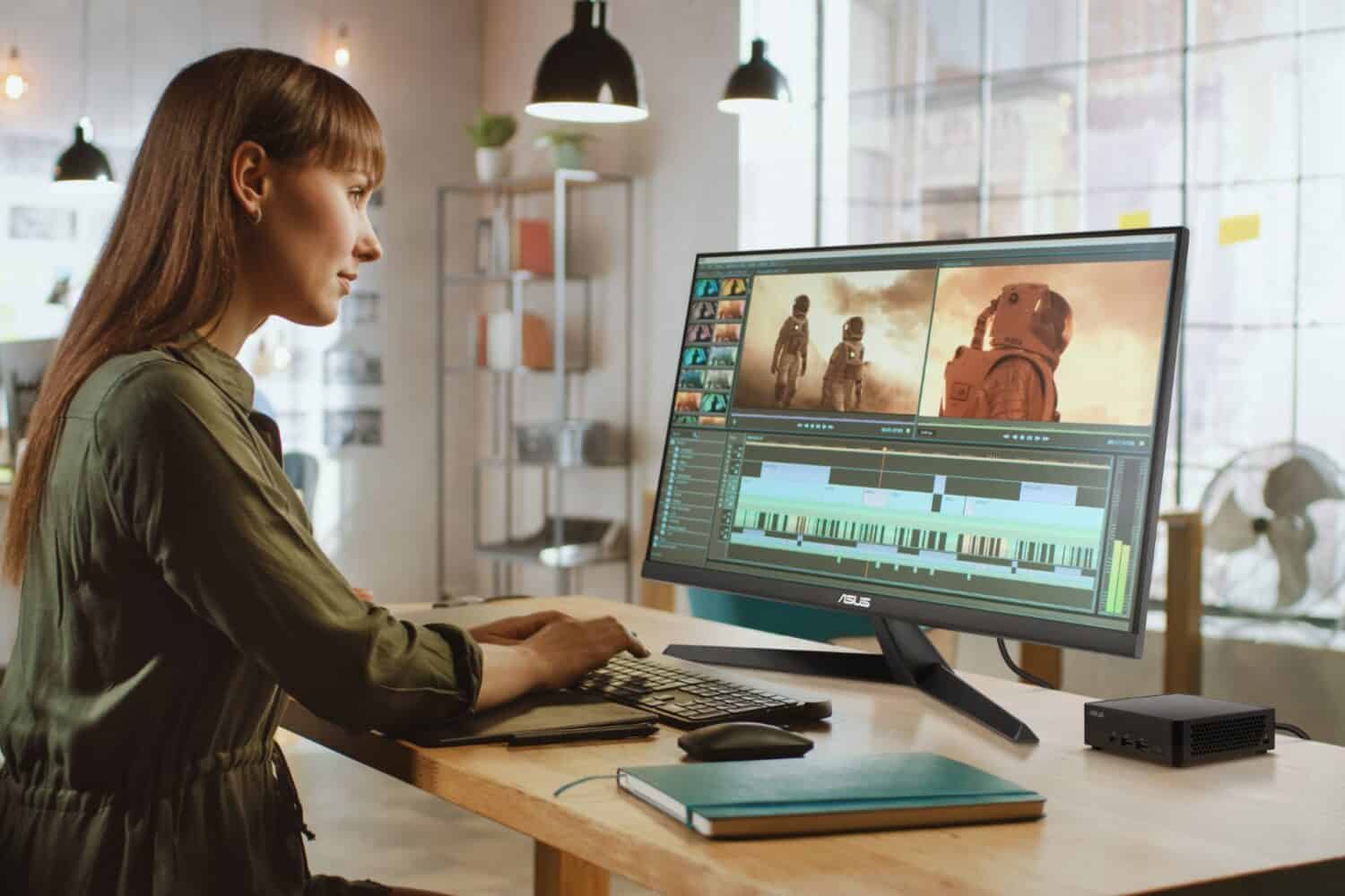 Een vrouw bewerkt videobeelden op een ASUS NUC 14 Pro. Het grote beeldscherm van de computer schittert in een moderne kantooromgeving.